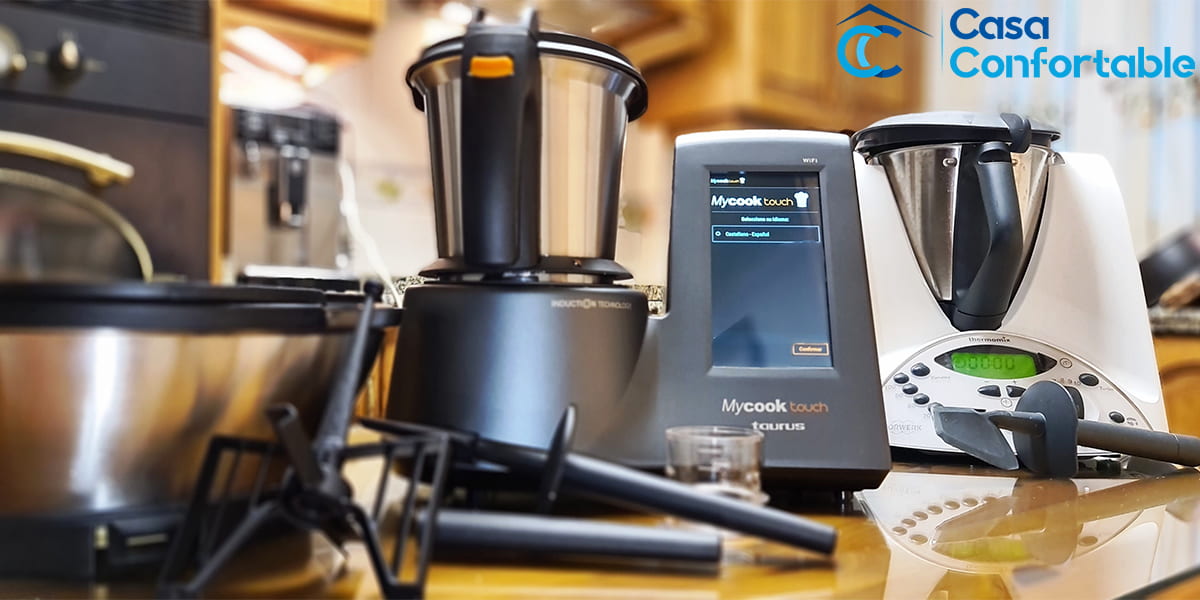 El Mycook Touch encendido junto a un Thermomix y sus accesorios, en la encimera de casa